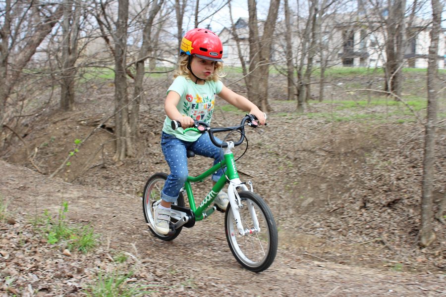 girl riding woom 3 16 inch bike on a dirt trail
