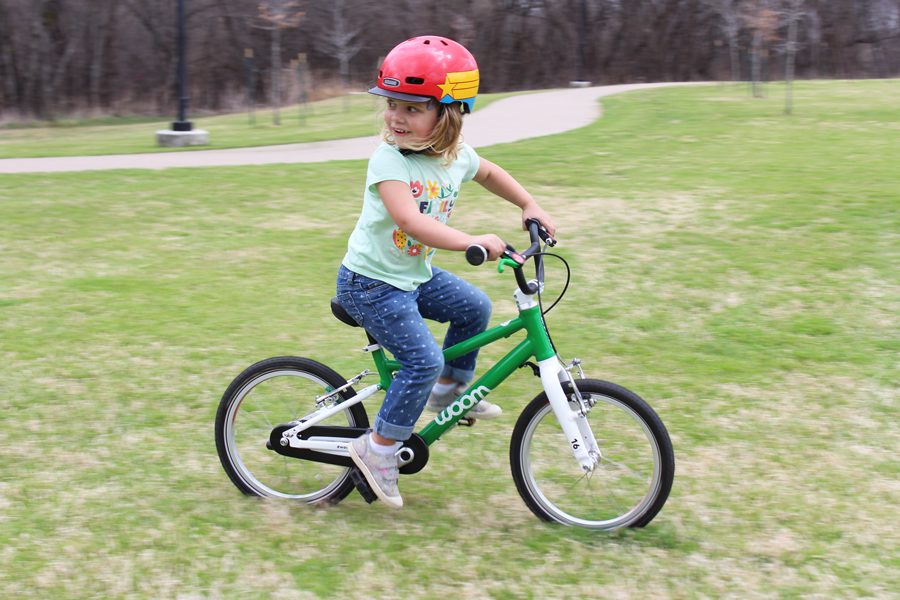 child riding green woom 3 across the grass