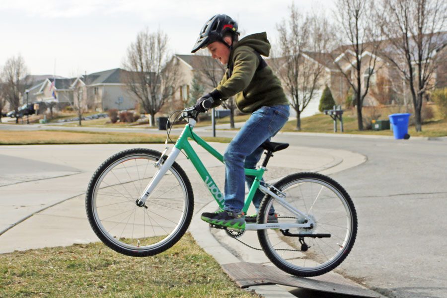 boy jumping the woom 5 bikes on a small ramp