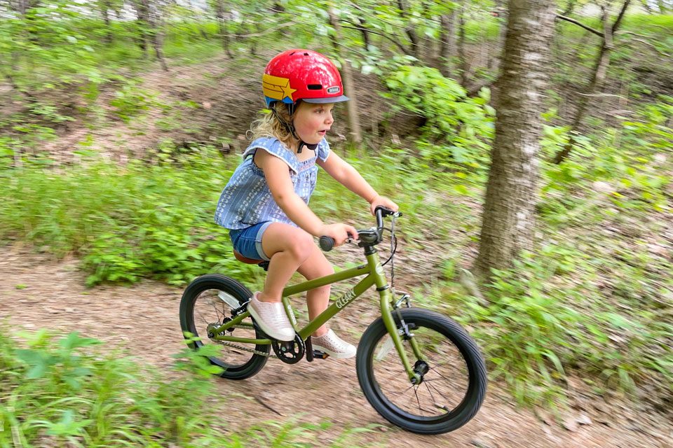 3 year old riding Cleary Hedgehog on a dirt path through the forest