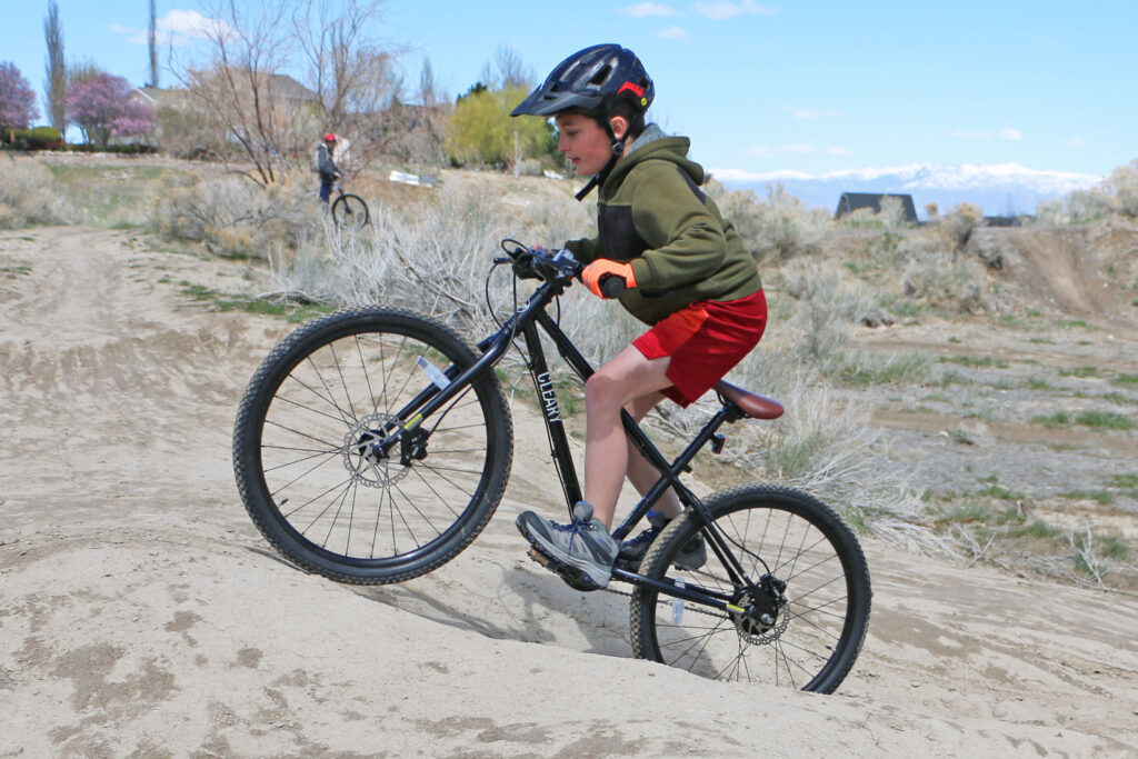 boy riding up a steep hill on the Cleary Meerkat 24 inch kids bike