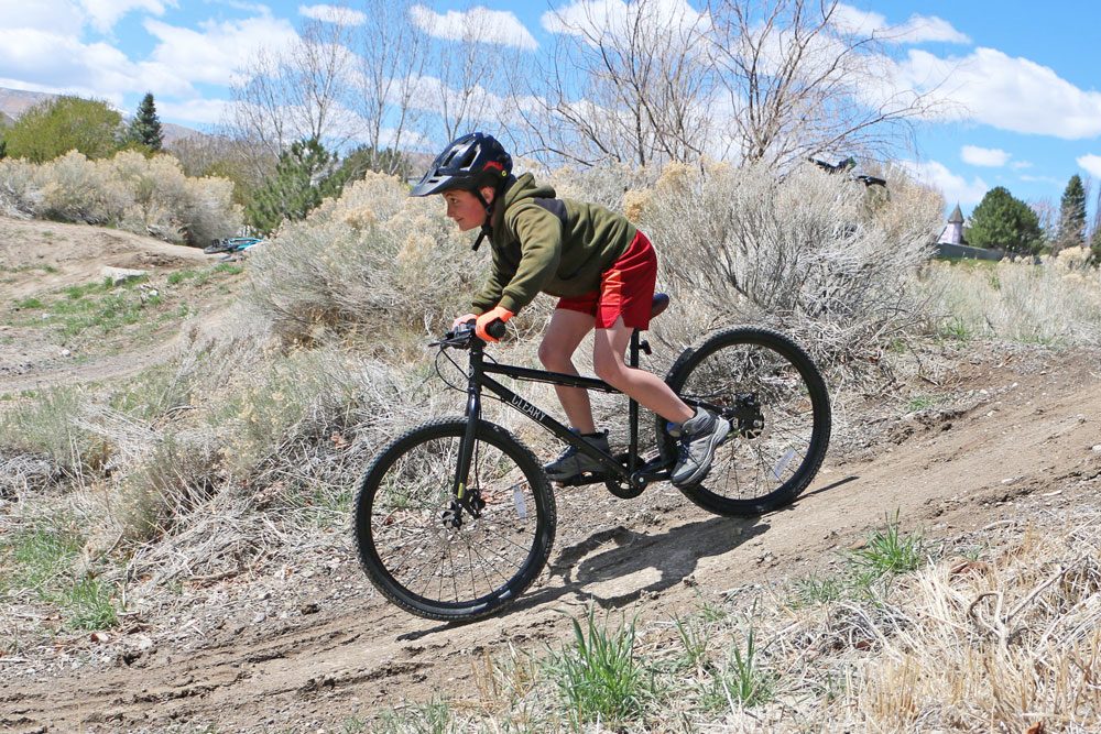 boy riding a Cleary 24 inch Meerkat down a dirt hill