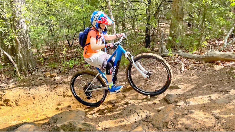 child pedaling up a hill on the woom up electric bike for kids
