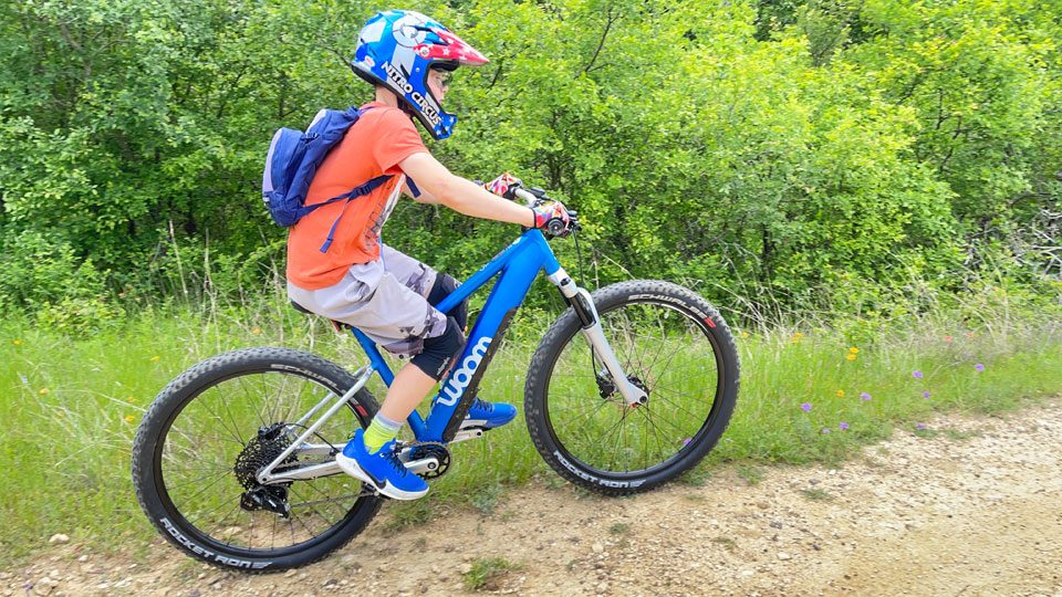 Boy riding his woom UP ebike on a mountain bike trail