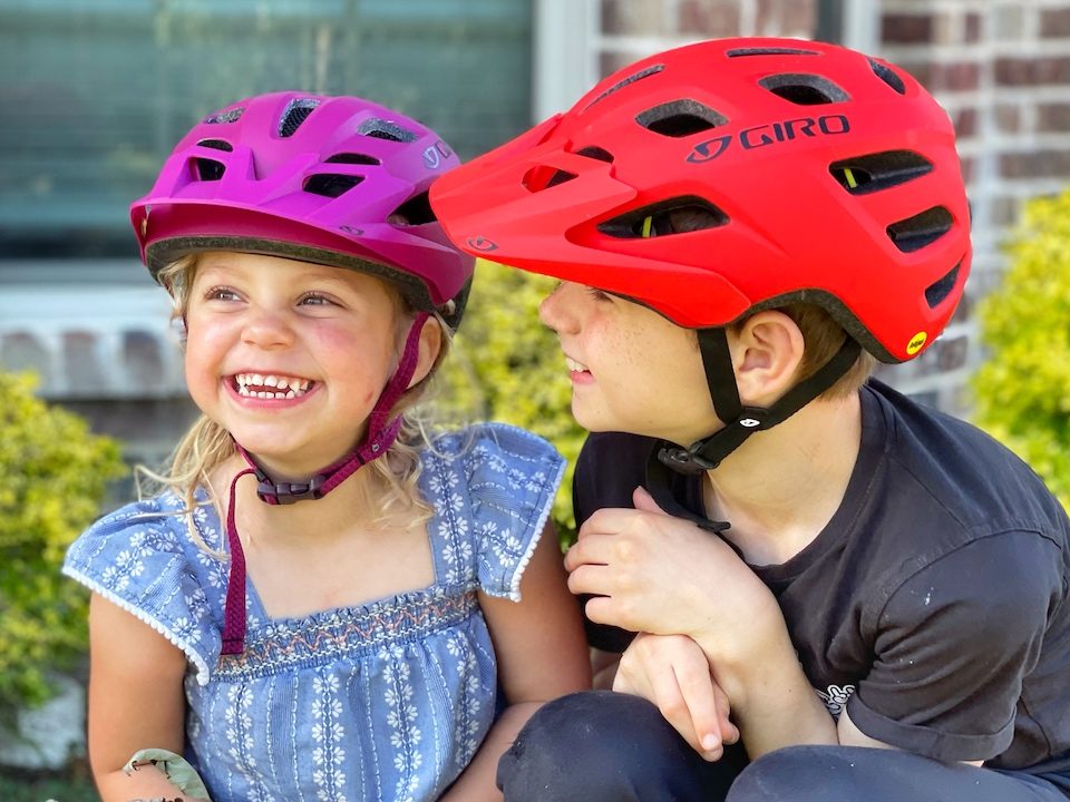 Brother and sister wearing Giro Tremor MIPS helmets in child and youth sizes
