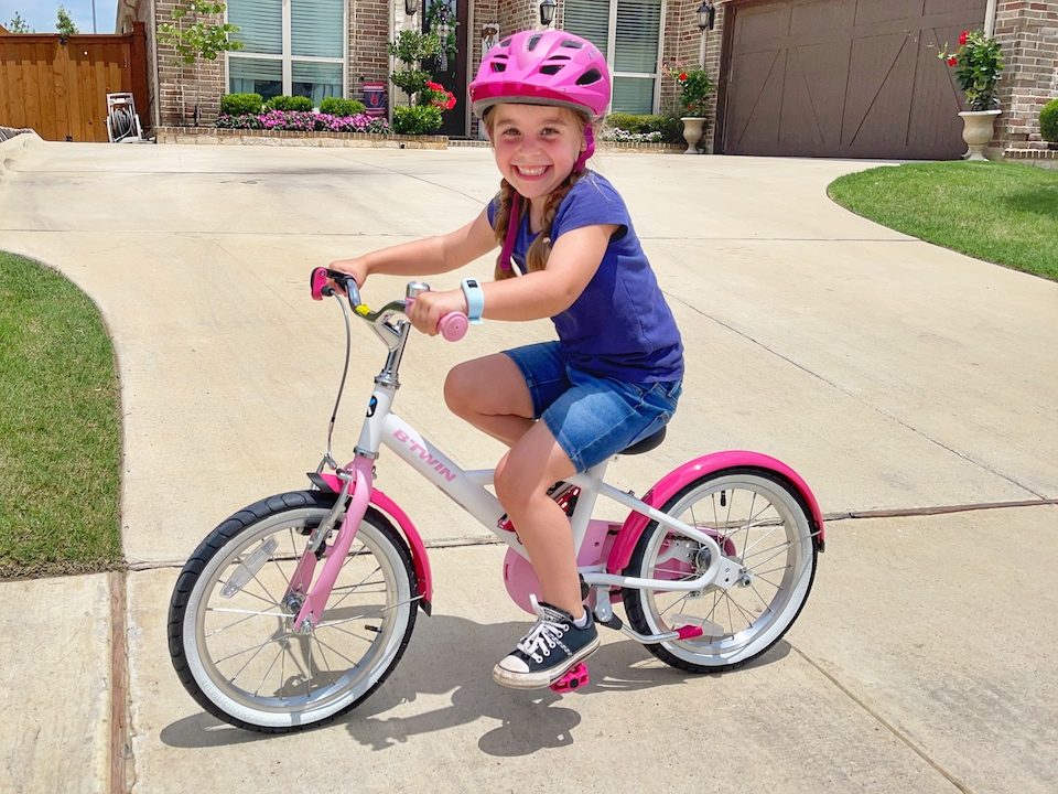 Child pedaling with big smile on her face as she just learned to ride a bike