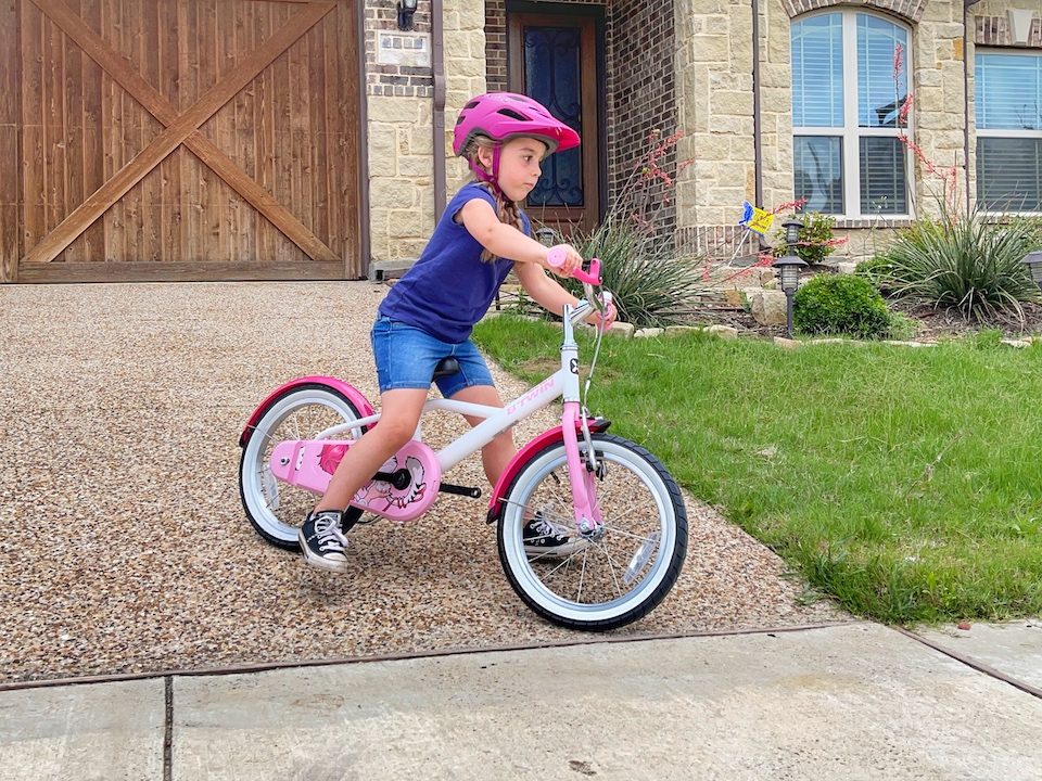 Child on a bike without pedal, coasting down the driveway