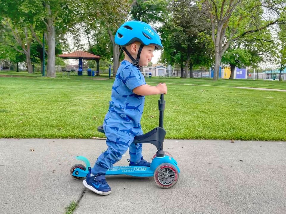 1 year old riding Micro Mini 3 in 1 Deluxe, sitting on seat and scooting along
