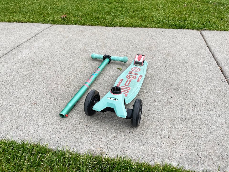 Handlebar of Micro Mini scooter laying next to the foot deck of the scooter