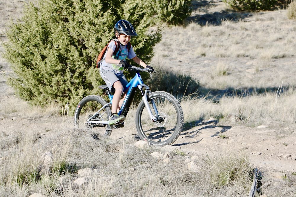 Boy grinning while riding woom up 5 24 inch electric mountain bike