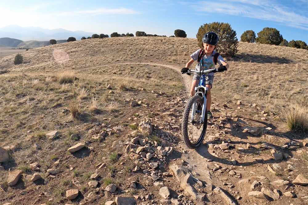 Boy reach the top of a rocky hill on the woom UP ebike