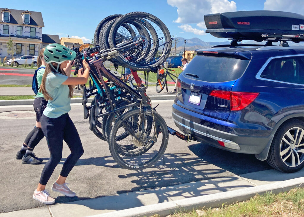 two girls pushing up the alta 6 capacity vertical bike rack