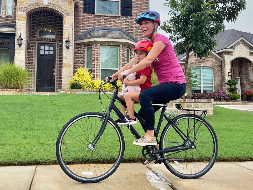 Mom riding happily with her child on the UrRider child bike seat