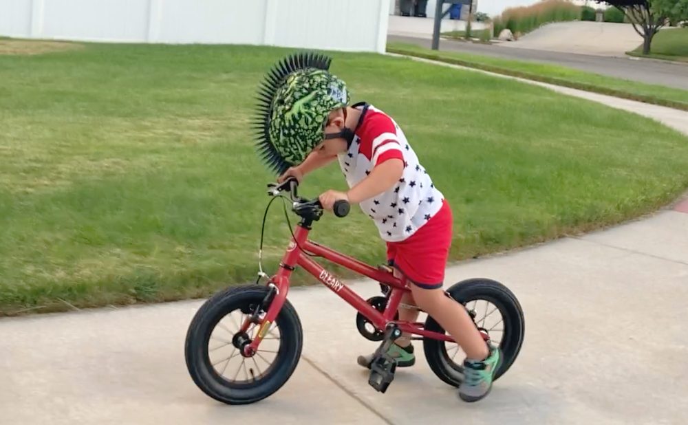boy riding the woom 2 with his feet pushing the bike behind the pedals