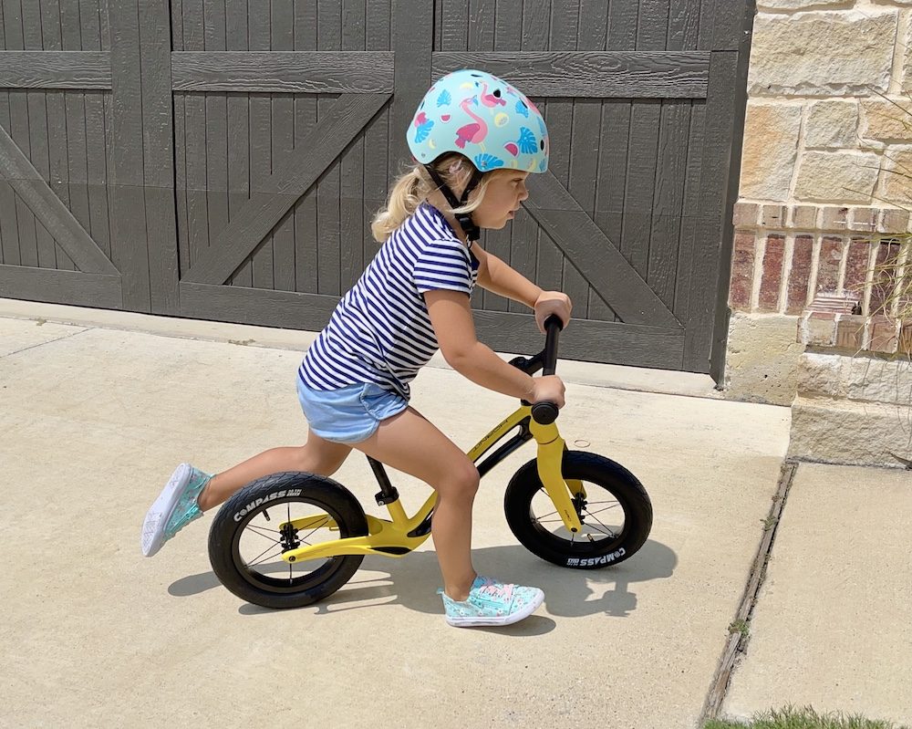 Toddler running up driveway on Hornit balance bike