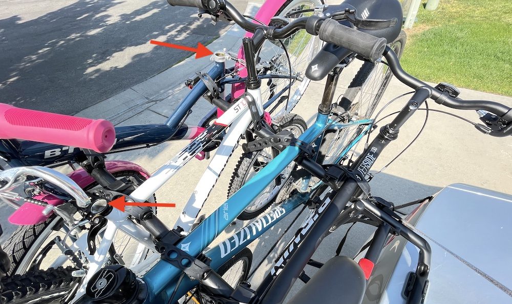 Four bikes loaded on a trunk bike rack. One bike has the saddle removed for easier loading.