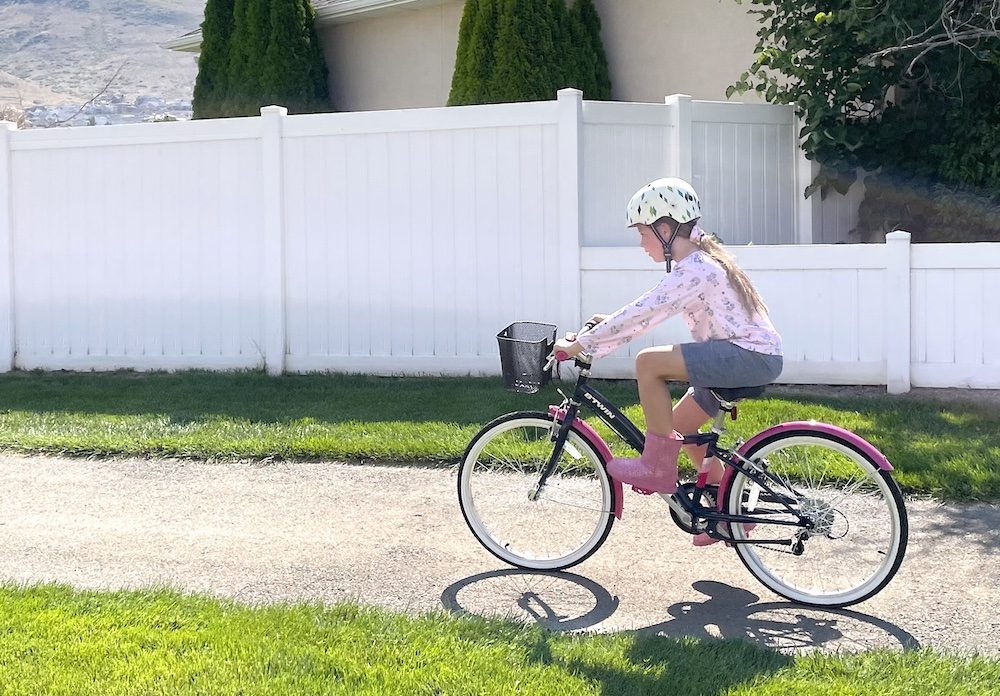 girl riding the btwin Original 24 bike on a paved path