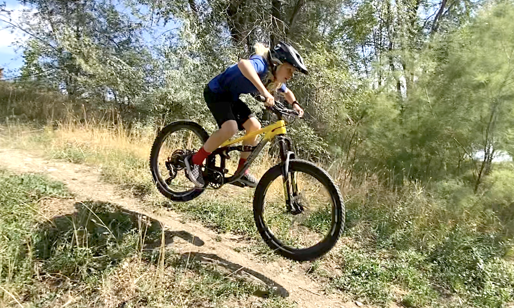 young rider riding downhill on a full suspension 24 inch bike