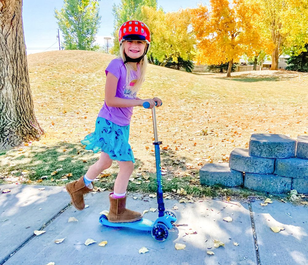 Girl riding Micro Maxi scooter on the sidewalk