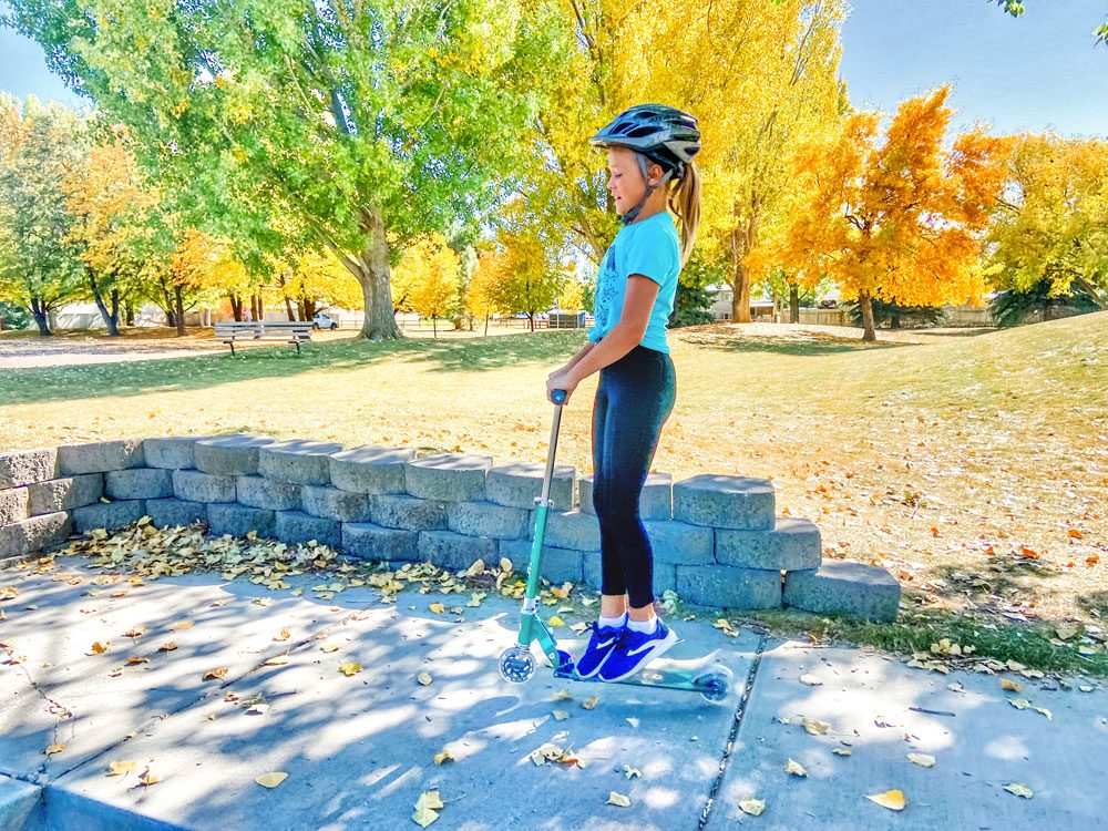 Girl jumping in the air while riding the Micro Sprite scooter