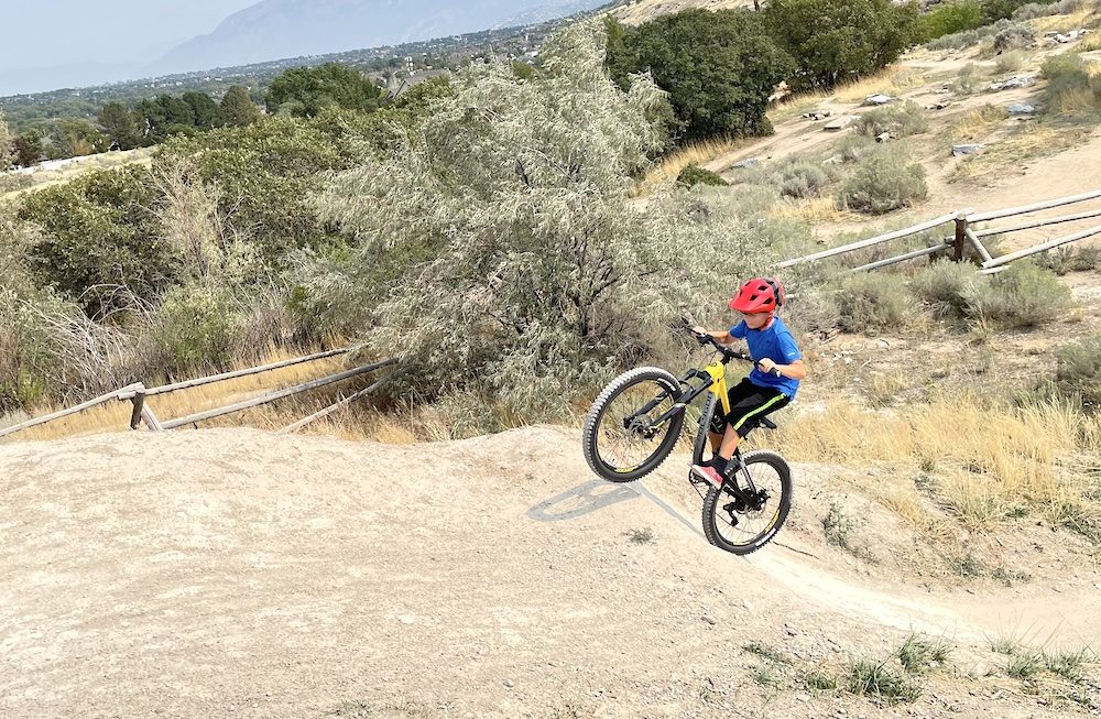 boy riding up a steep jump on a 24 inch full suspension kids mountain bike