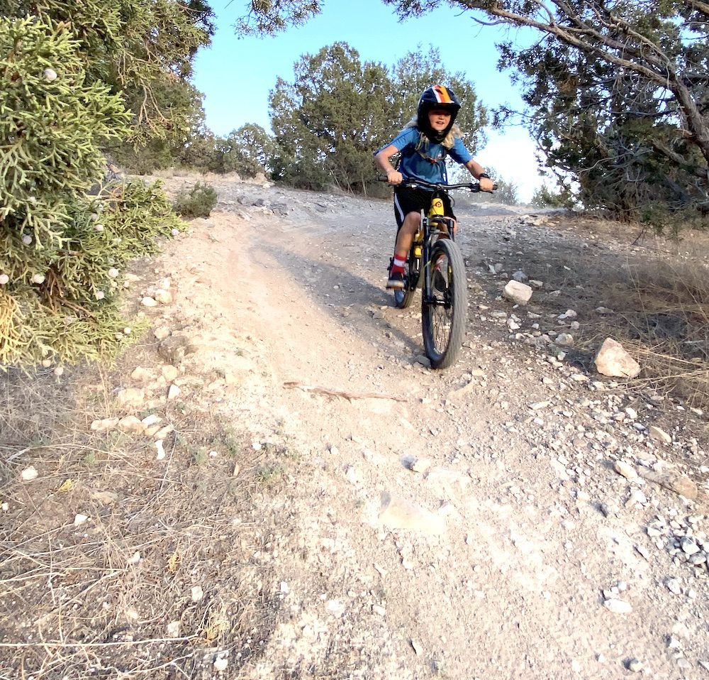 riding down a rocky section of trail on the polygon siskiu kids mountain bike