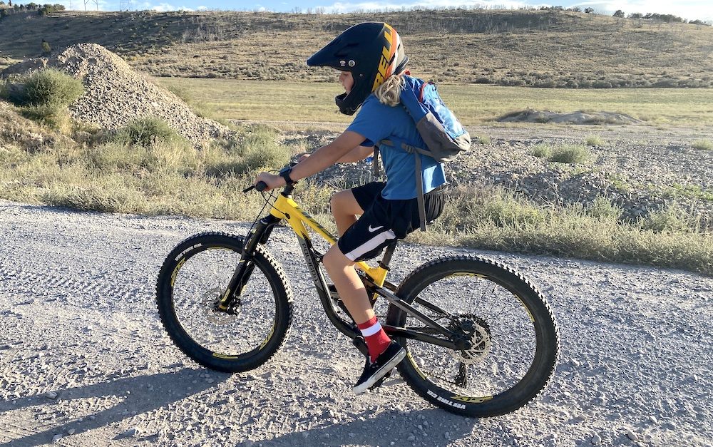 boy riding on a dirt trail while on the polygon siskiu full suspension kids mountain bike