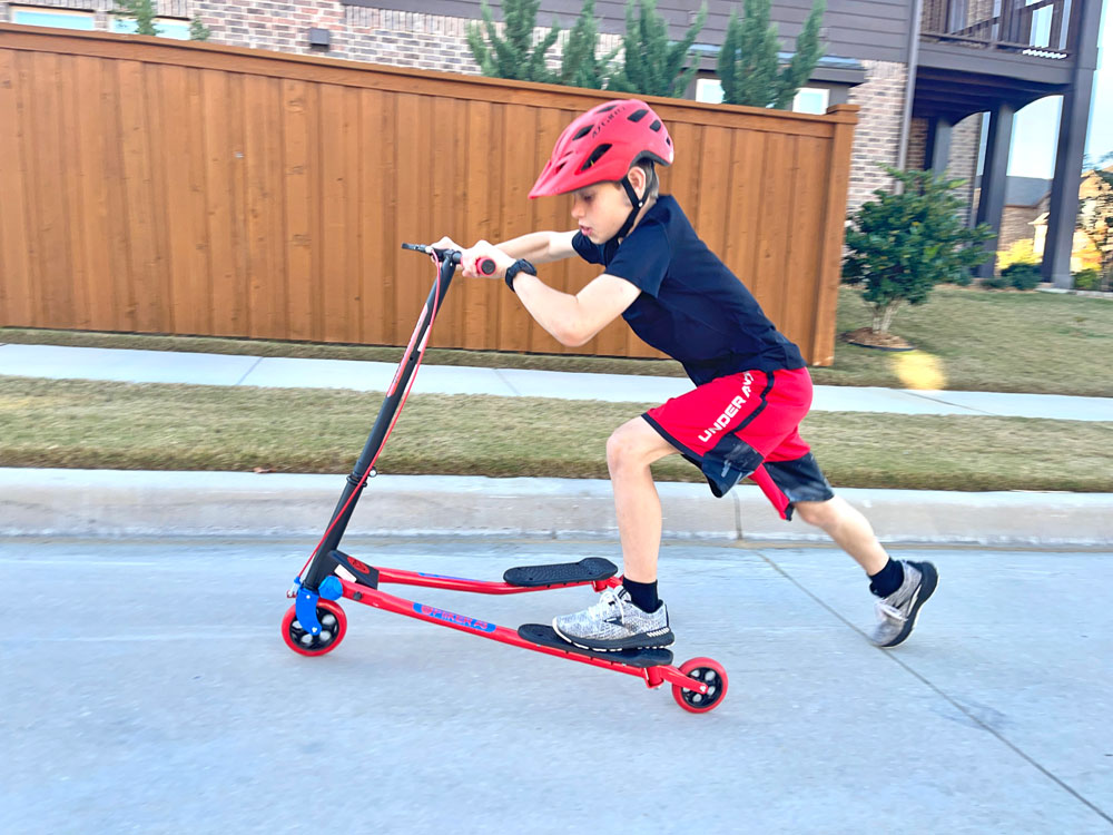 Boy riding Y Fliker Scooter uphill and pushing off the ground with his foot