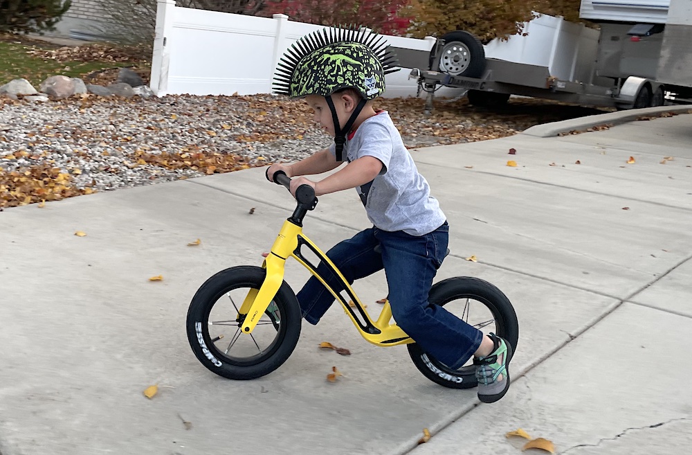 riding a yellow AIRO Hornit balance bike