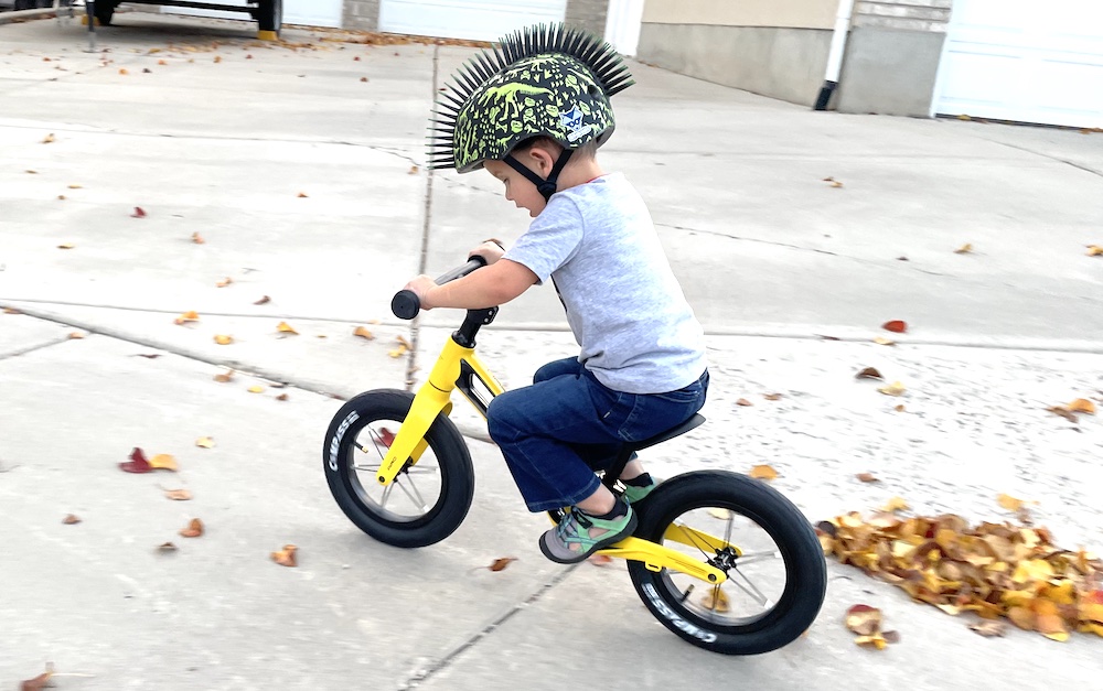 riding the AIRO Hornit balance bike with feet up on the foot rests