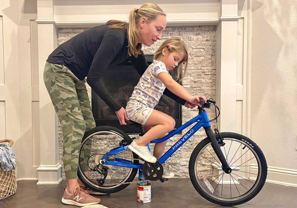 Child riding Prevelo Alpha Three in place, using cans as a make-shift trainer