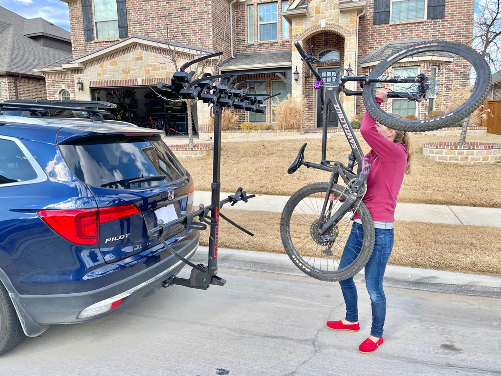 Woman lifting bike over her head to hang it on the Yakima HangTight