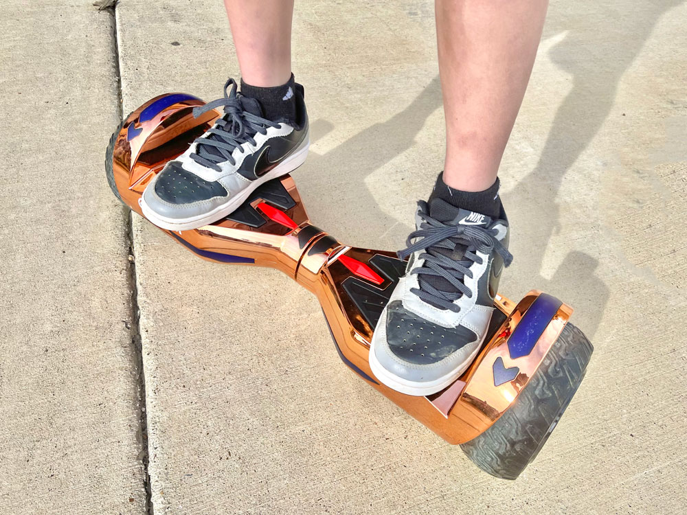 kid riding GoTrax Nova Pro bluetooth hoverboard in rose gold on sidewalk