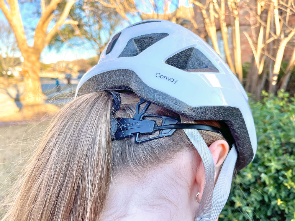 Woman wearing high ponytail threaded through the back of her bike helmet
