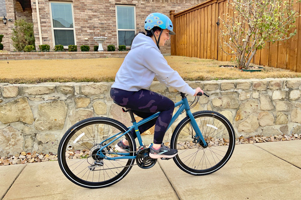 Woman riding REI CTY 1.1 hybrid bike on the sidewalk