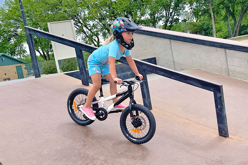 Child rider standing up in the saddle while going down a ramp on the Commencal Ramones 16.