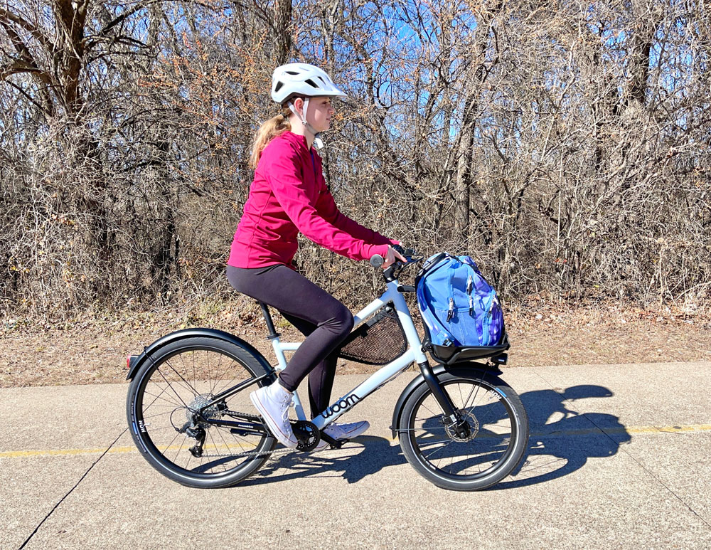 13 year old girl riding woom NOW 6 26 inch kids commuter bike on a paved path