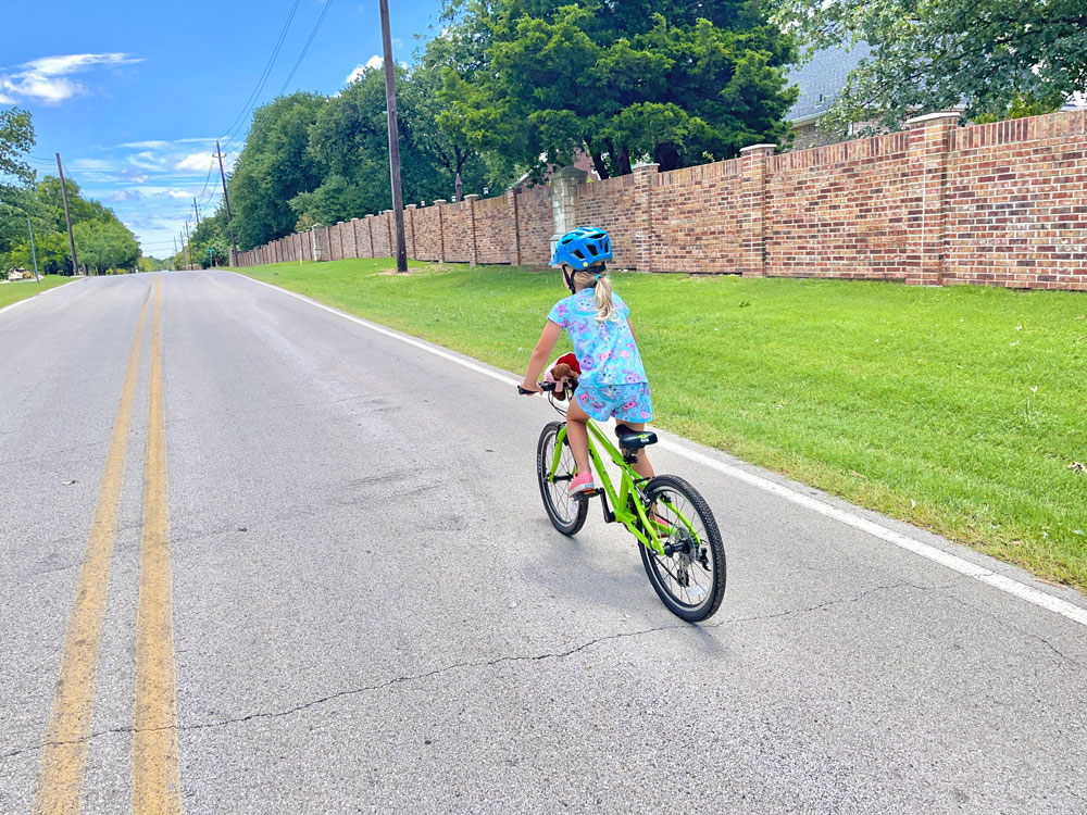 Girl stands up in saddle on Frog 52 to climb up a hill