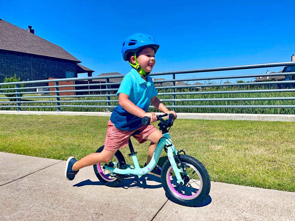 young boy running on Guardian balance bike down the sidewalk