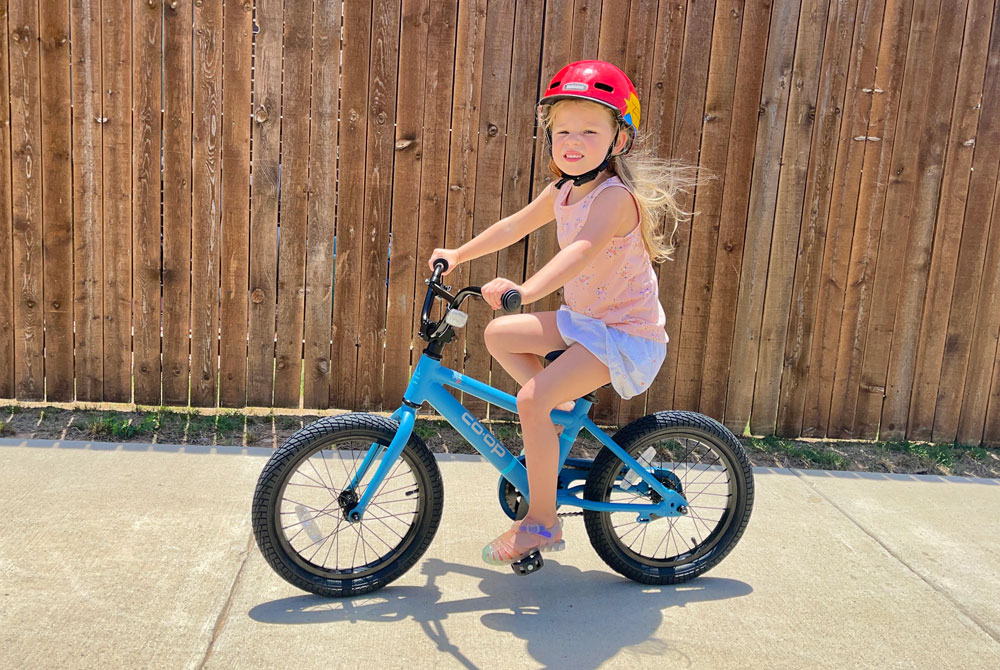 4 year old girl riding REI REV 16 down the sidewalk