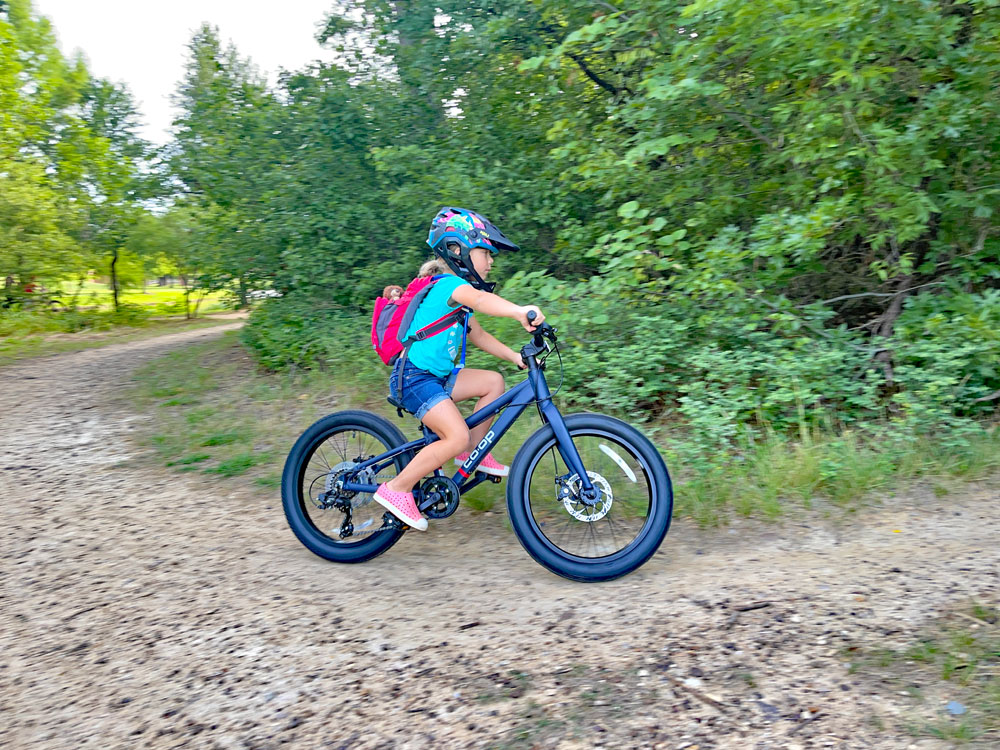 Child riding REI Co-Op Cycles REV Plus 6-speed 20 inch bike on a dirt trail