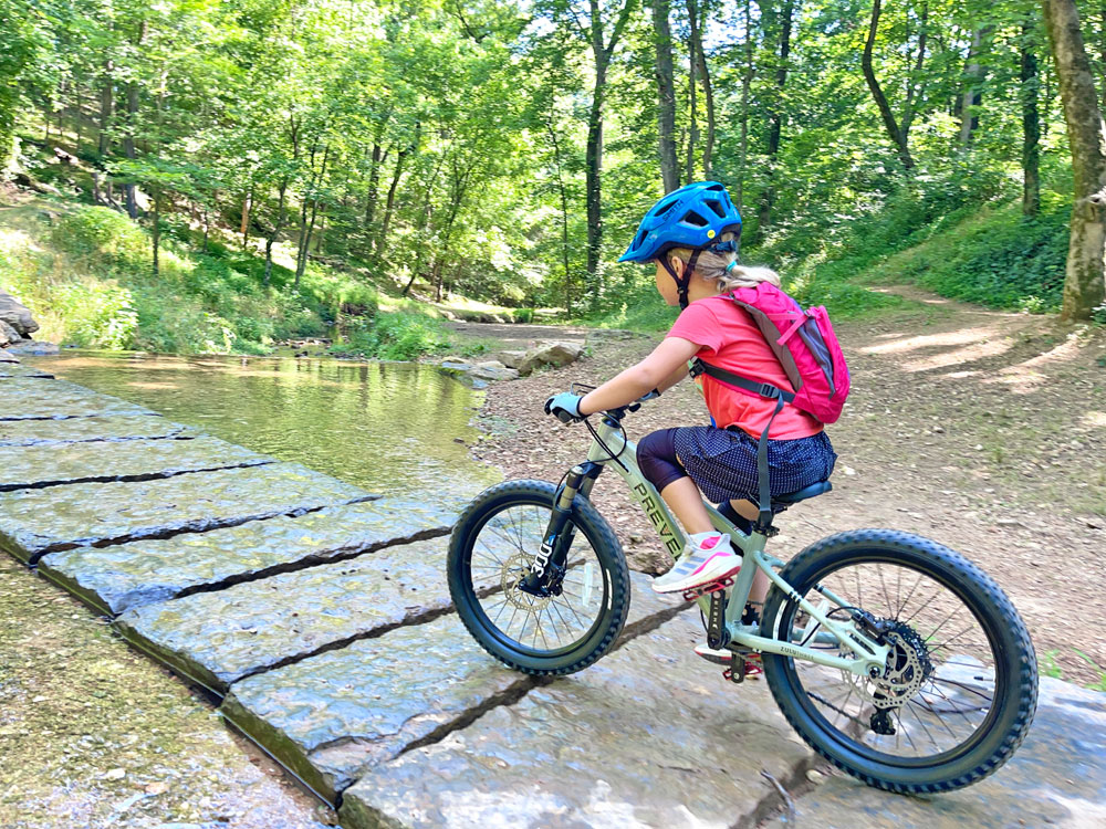 Child riding over rock bridge at Black Apple Creek trail in Bentonville