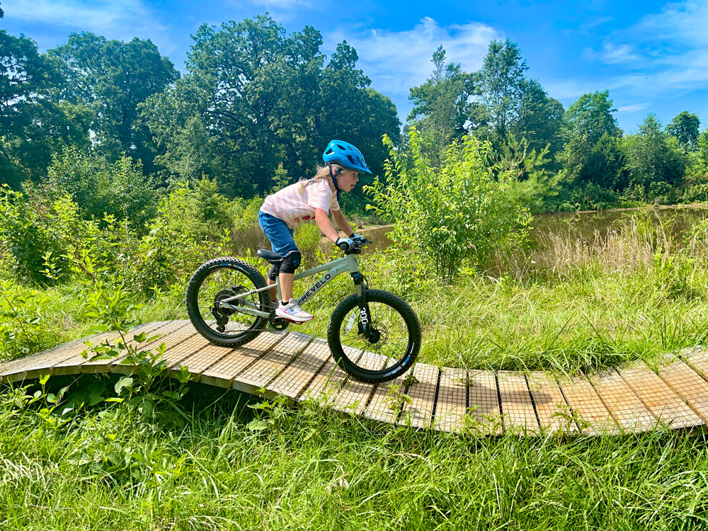 Child riding on wooden roller on Prevelo Zulu Three 20" kids mountain bike
