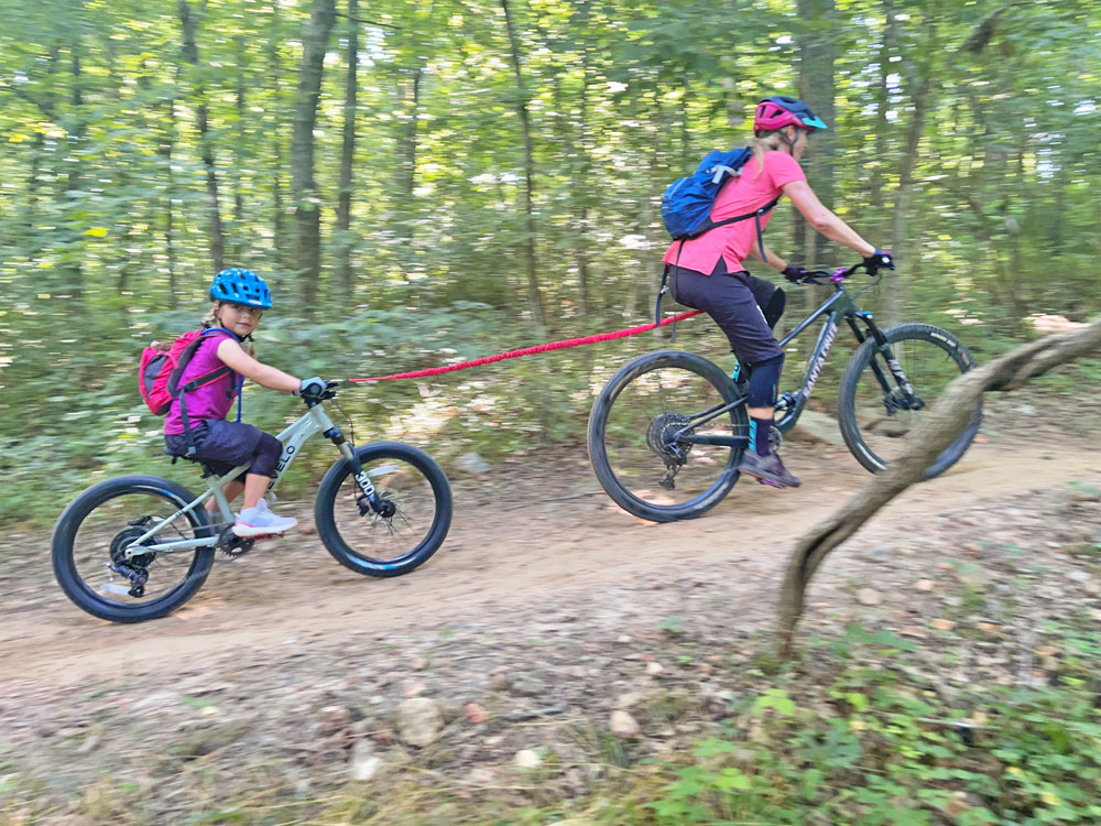 Girl being towed up a hill by her other owith TowWhee bike tow rope
