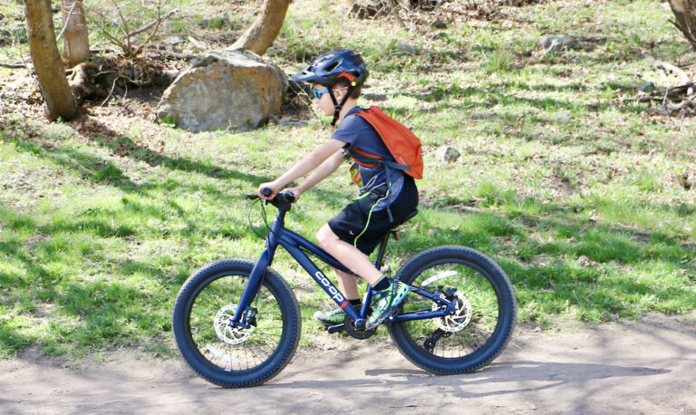 7 year old riding REI REV 20 6-speed bike on a wide dirt trail