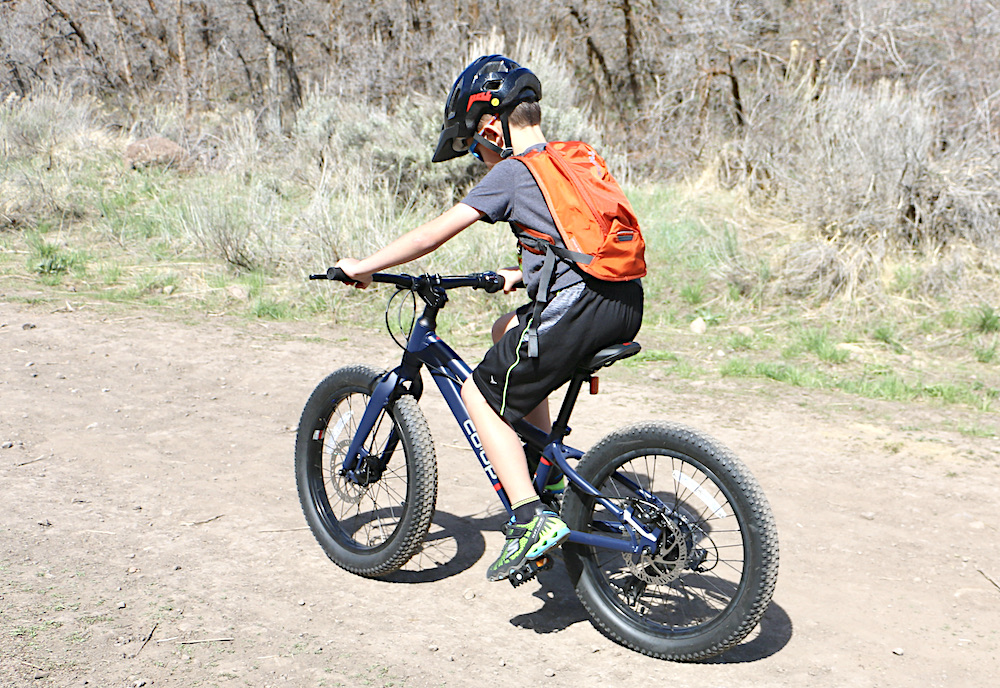 boy riding the REI REV 20" 6-speed plus kids mountain bike on a dirt trail