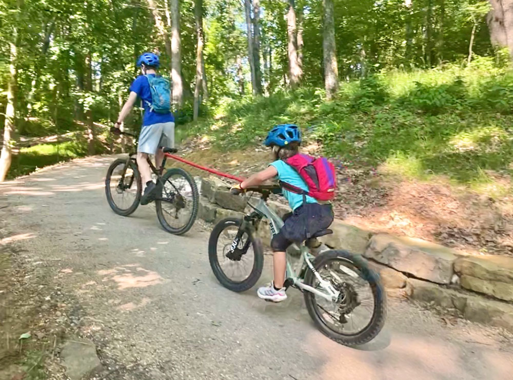 Teenager pulling little sister up a hill using TowWhee tow rope