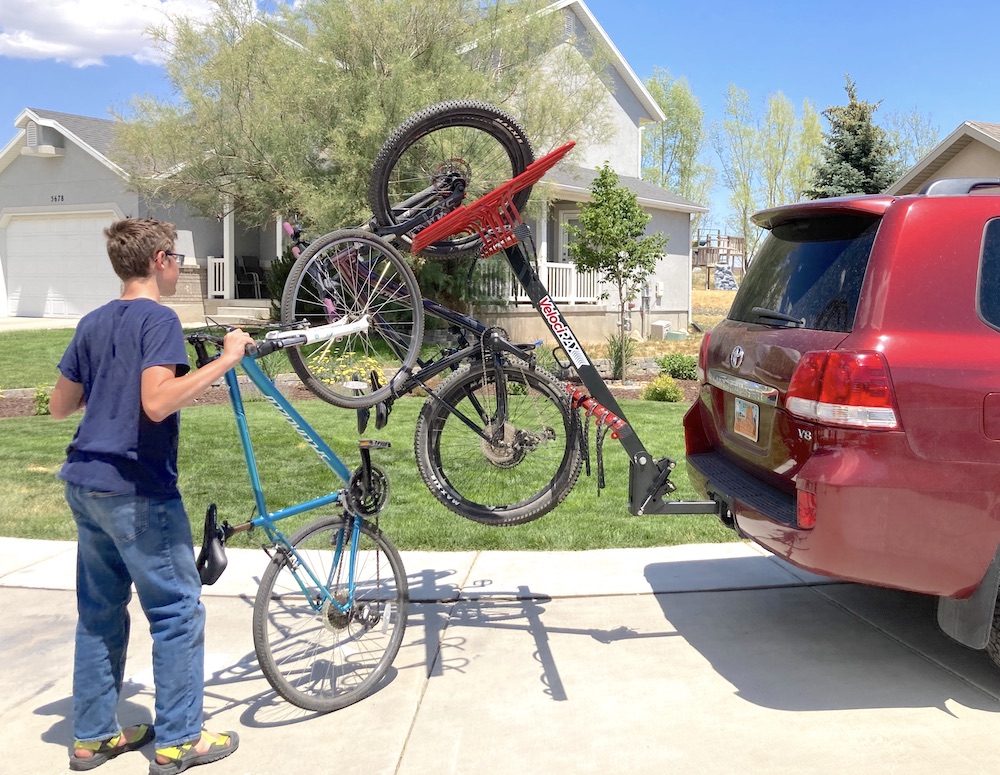 boy trying to load a bike onto the Velocirax attached to a Land Cruiser