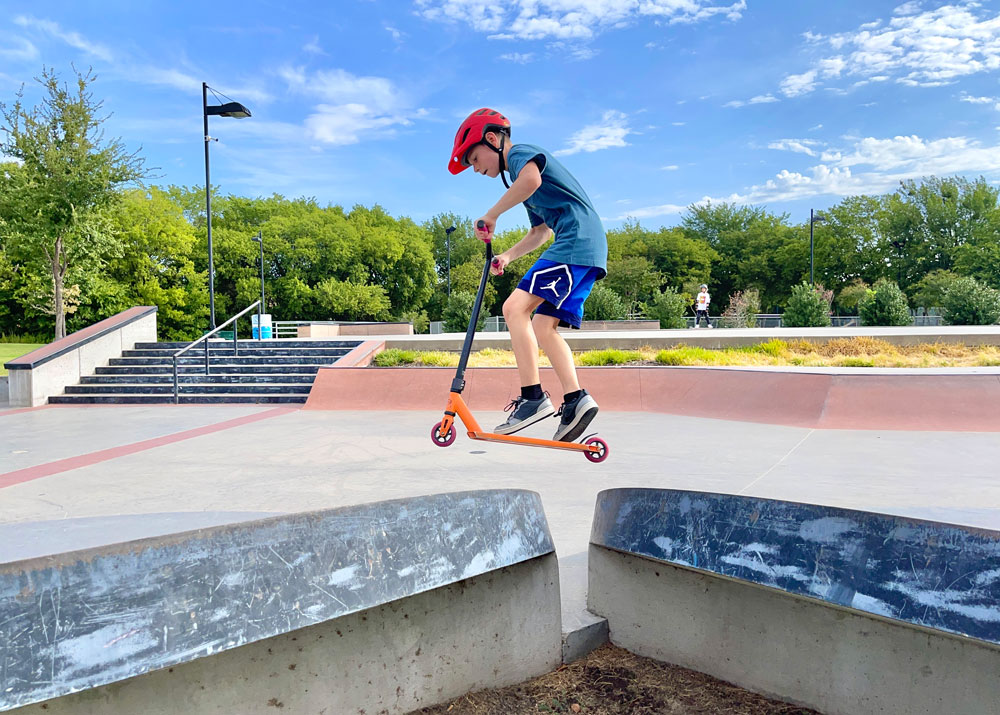 10 year old boy riding Fuzion X5 at the skatepark, jumping over an obstacle