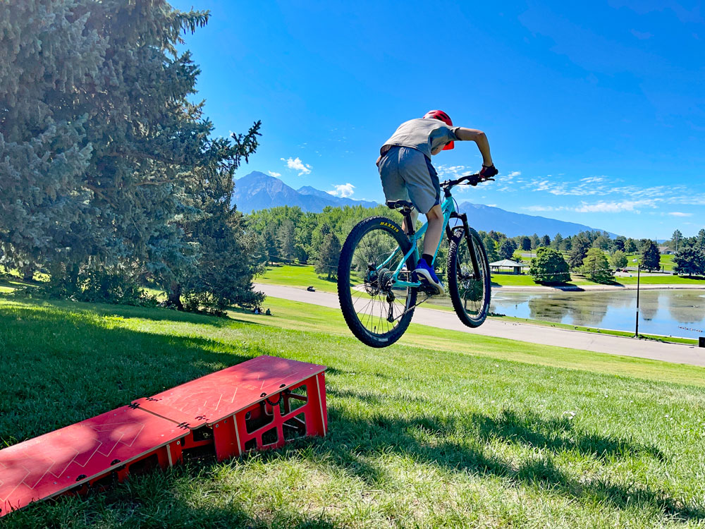 Boy jumping off portable ramp on Pello Roovi 27.5" kids bike